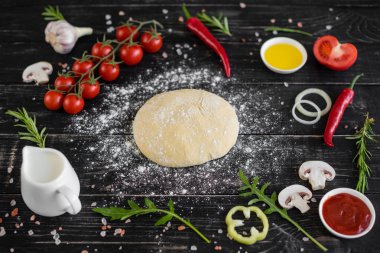 Hamur ve üretime pizza sebze hazırlanması. Ahşap arka plan üzerinde pizza üretimi için malzemeler