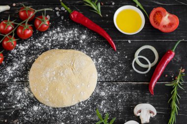 Hamur ve üretime pizza sebze hazırlanması. Ahşap arka plan üzerinde pizza üretimi için malzemeler