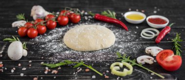 Hamur ve üretime pizza sebze hazırlanması. Ahşap arka plan üzerinde pizza üretimi için malzemeler