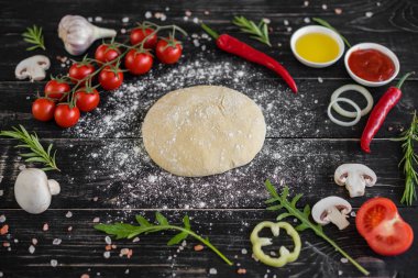 Hamur ve üretime pizza sebze hazırlanması. Ahşap arka plan üzerinde pizza üretimi için malzemeler