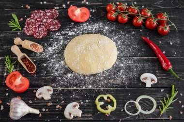 Hamur ve üretime pizza sebze hazırlanması. Ahşap arka plan üzerinde pizza üretimi için malzemeler