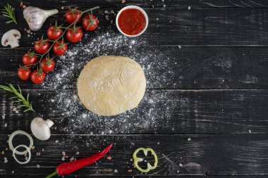 Hamur ve üretime pizza sebze hazırlanması. Ahşap arka plan üzerinde pizza üretimi için malzemeler