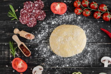 Hamur ve üretime pizza sebze hazırlanması. Ahşap arka plan üzerinde pizza üretimi için malzemeler