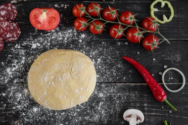 Hamur ve üretime pizza sebze hazırlanması. Ahşap arka plan üzerinde pizza üretimi için malzemeler