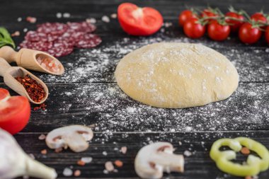 Hamur ve üretime pizza sebze hazırlanması. Ahşap arka plan üzerinde pizza üretimi için malzemeler