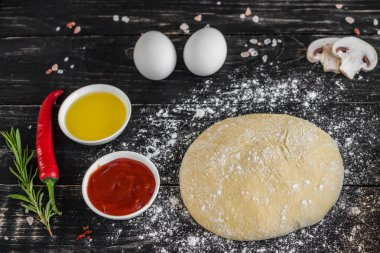 Hamur ve üretime pizza sebze hazırlanması. Ahşap arka plan üzerinde pizza üretimi için malzemeler