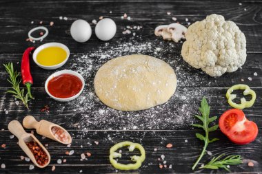 Hamur ve üretime pizza sebze hazırlanması. Ahşap arka plan üzerinde pizza üretimi için malzemeler