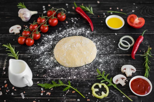 Preparation of the dough and vegetables to production of pizza. Ingredients for production of pizza on a wooden background