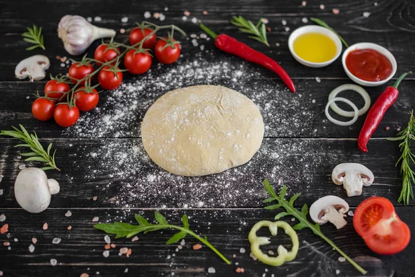 Hamur ve üretime pizza sebze hazırlanması. Ahşap arka plan üzerinde pizza üretimi için malzemeler