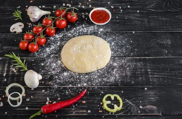 Hamur ve üretime pizza sebze hazırlanması. Ahşap arka plan üzerinde pizza üretimi için malzemeler