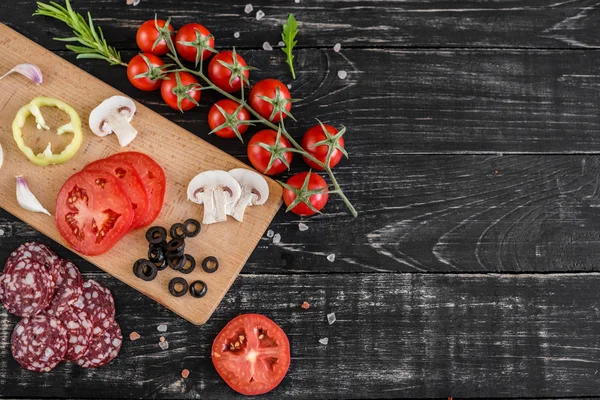 Preparation of the dough and vegetables to production of pizza. Ingredients for production of pizza on a wooden background