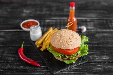 Et ve sebze karanlık bir arka plan ile lezzetli hamburger. Fast food. Arka plan olarak kullanılabilir