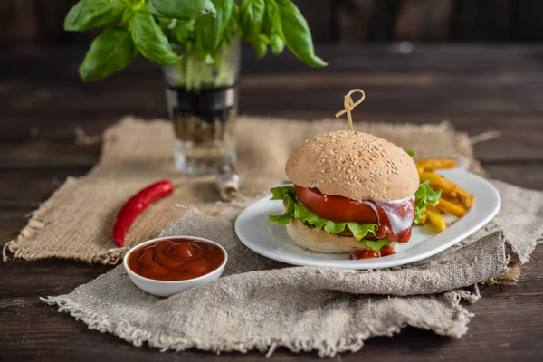 Tasty hamburger with meat and vegetables against a dark background. Fast food. It can be used as a background