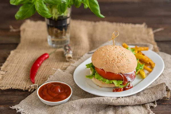 Tasty hamburger with meat and vegetables against a dark background. Fast food. It can be used as a background