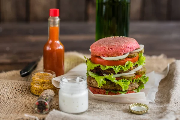 Tasty hamburger with meat and vegetables against a dark background. Fast food. It can be used as a background