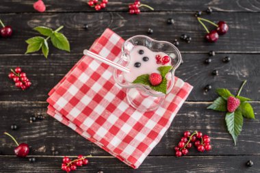 Ahududu farklı meyve ahşap bir zemin üzerine bir bardak dan güler yüzlü. Arka plan olarak kullanılabilir