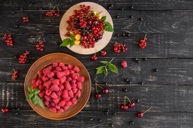 Ahududu, kiraz, frenk üzümü, karanlık bir arka plan karşı ahşap bir tabakta blackcurrant. Arka plan olarak kullanılabilir