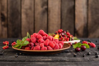 Ahududu, kiraz, frenk üzümü, karanlık bir arka plan karşı ahşap bir tabakta blackcurrant. Arka plan olarak kullanılabilir