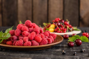 Ahududu, kiraz, frenk üzümü, karanlık bir arka plan karşı ahşap bir tabakta blackcurrant. Arka plan olarak kullanılabilir