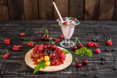 Ahududu, kiraz, frenk üzümü, karanlık bir arka plan karşı ahşap bir tabakta blackcurrant. Arka plan olarak kullanılabilir