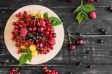 Ahududu, kiraz, frenk üzümü, karanlık bir arka plan karşı ahşap bir tabakta blackcurrant. Arka plan olarak kullanılabilir