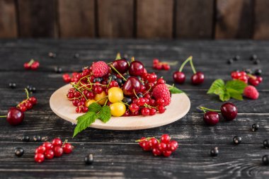 Ahududu, kiraz, frenk üzümü, karanlık bir arka plan karşı ahşap bir tabakta blackcurrant. Arka plan olarak kullanılabilir