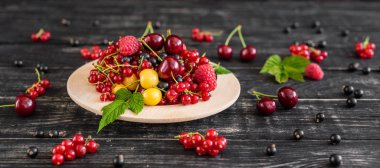 Ahududu, kiraz, frenk üzümü, karanlık bir arka plan karşı ahşap bir tabakta blackcurrant. Arka plan olarak kullanılabilir