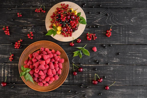 Ahududu, kiraz, frenk üzümü, karanlık bir arka plan karşı ahşap bir tabakta blackcurrant. Arka plan olarak kullanılabilir