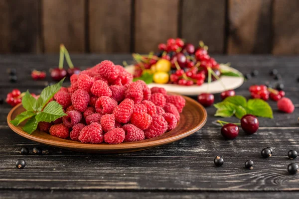 Ahududu, kiraz, frenk üzümü, karanlık bir arka plan karşı ahşap bir tabakta blackcurrant. Arka plan olarak kullanılabilir