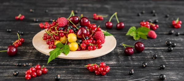Ahududu, kiraz, frenk üzümü, karanlık bir arka plan karşı ahşap bir tabakta blackcurrant. Arka plan olarak kullanılabilir