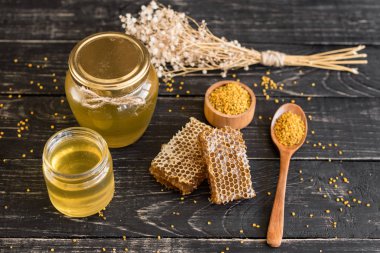 Banka, peteğin ve polen ahşap bir masa üzerinde güzel şeffaf tatlım. Arka plan olarak kullanılabilir