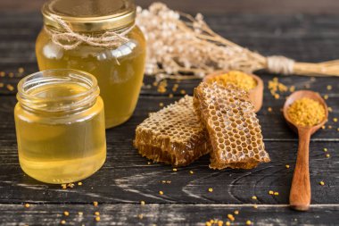 Banka, peteğin ve polen ahşap bir masa üzerinde güzel şeffaf tatlım. Arka plan olarak kullanılabilir