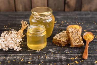 Banka, peteğin ve polen ahşap bir masa üzerinde güzel şeffaf tatlım. Arka plan olarak kullanılabilir