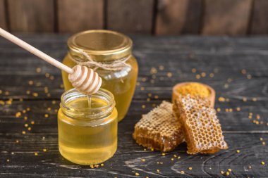 Banka, peteğin ve polen ahşap bir masa üzerinde güzel şeffaf tatlım. Arka plan olarak kullanılabilir