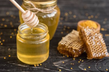 Banka, peteğin ve polen ahşap bir masa üzerinde güzel şeffaf tatlım. Arka plan olarak kullanılabilir