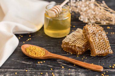 Banka, peteğin ve polen ahşap bir masa üzerinde güzel şeffaf tatlım. Arka plan olarak kullanılabilir