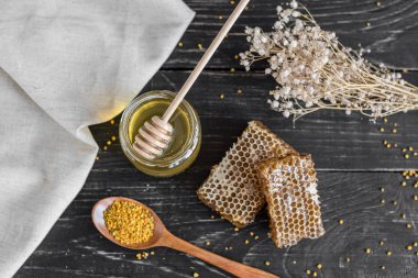 Banka, peteğin ve polen ahşap bir masa üzerinde güzel şeffaf tatlım. Arka plan olarak kullanılabilir