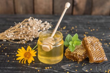 Banka, peteğin ve polen ahşap bir masa üzerinde güzel şeffaf tatlım. Arka plan olarak kullanılabilir