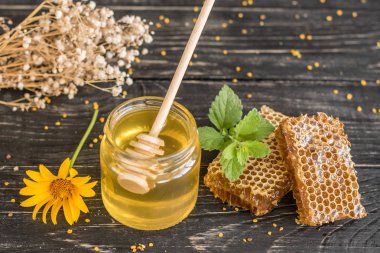 Banka, peteğin ve polen ahşap bir masa üzerinde güzel şeffaf tatlım. Arka plan olarak kullanılabilir