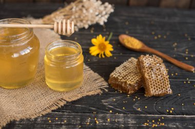 Banka, peteğin ve polen ahşap bir masa üzerinde güzel şeffaf tatlım. Arka plan olarak kullanılabilir