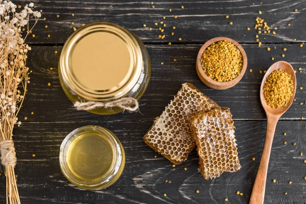 Banka, peteğin ve polen ahşap bir masa üzerinde güzel şeffaf tatlım. Arka plan olarak kullanılabilir