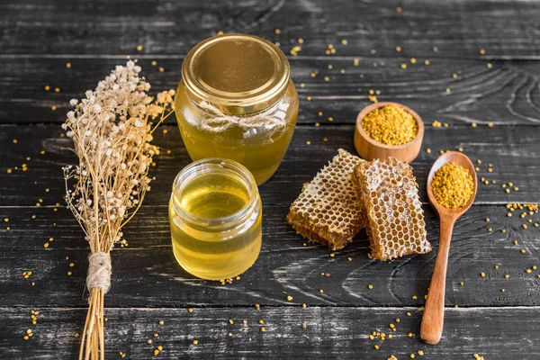 Banka, peteğin ve polen ahşap bir masa üzerinde güzel şeffaf tatlım. Arka plan olarak kullanılabilir