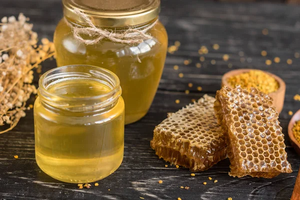 Banka, peteğin ve polen ahşap bir masa üzerinde güzel şeffaf tatlım. Arka plan olarak kullanılabilir