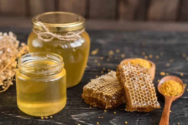 Banka, peteğin ve polen ahşap bir masa üzerinde güzel şeffaf tatlım. Arka plan olarak kullanılabilir