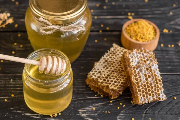 Banka, peteğin ve polen ahşap bir masa üzerinde güzel şeffaf tatlım. Arka plan olarak kullanılabilir