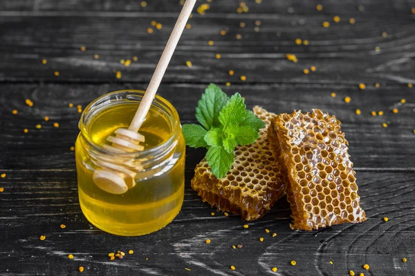 Banka, peteğin ve polen ahşap bir masa üzerinde güzel şeffaf tatlım. Arka plan olarak kullanılabilir