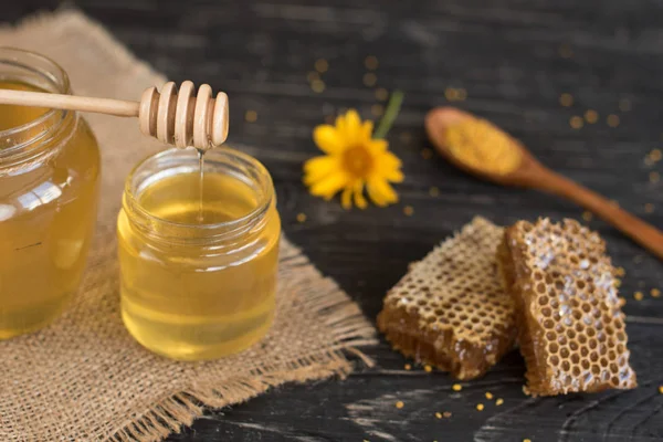 Banka, peteğin ve polen ahşap bir masa üzerinde güzel şeffaf tatlım. Arka plan olarak kullanılabilir