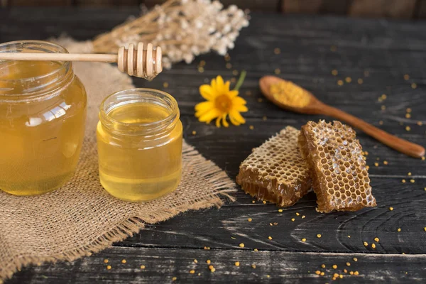 Banka, peteğin ve polen ahşap bir masa üzerinde güzel şeffaf tatlım. Arka plan olarak kullanılabilir