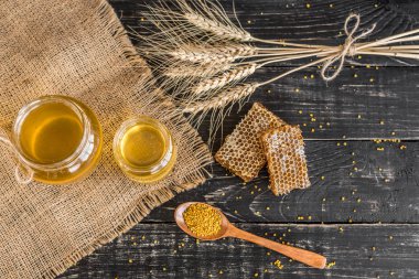 Banka, peteğin ve polen ahşap bir masa üzerinde güzel şeffaf tatlım. Arka plan olarak kullanılabilir