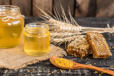 Banka, peteğin ve polen ahşap bir masa üzerinde güzel şeffaf tatlım. Arka plan olarak kullanılabilir